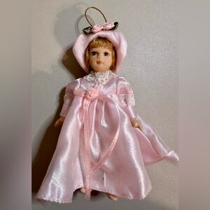 Adorable miniature porcelain doll, 5.5 inches tall, wearing a pink satin dress,